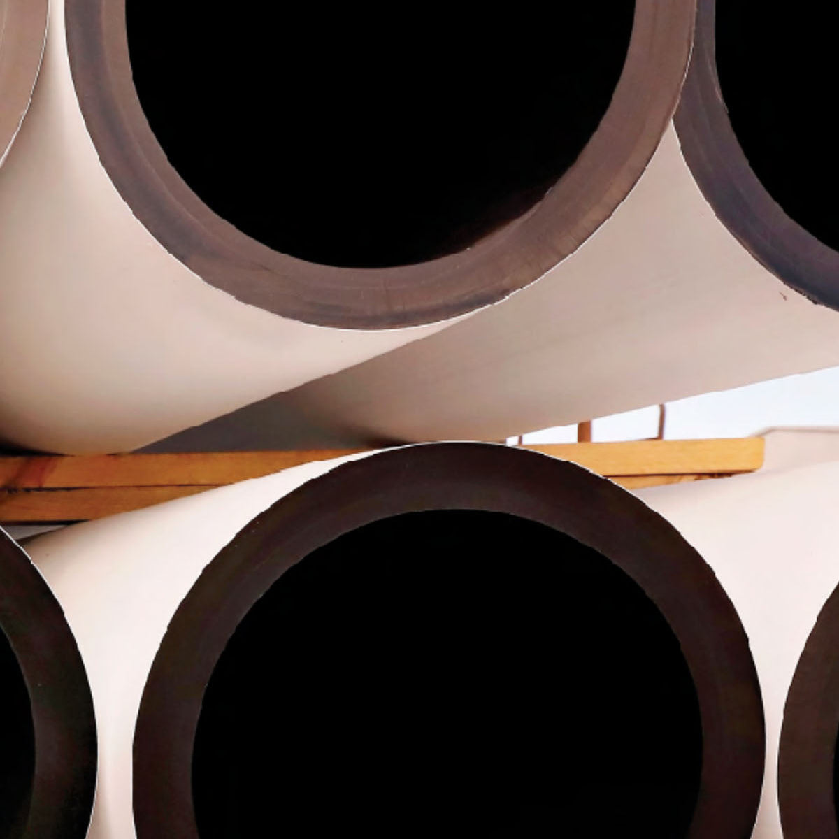 Stack of large white paper rolls with black circular patterns on a wooden surface.